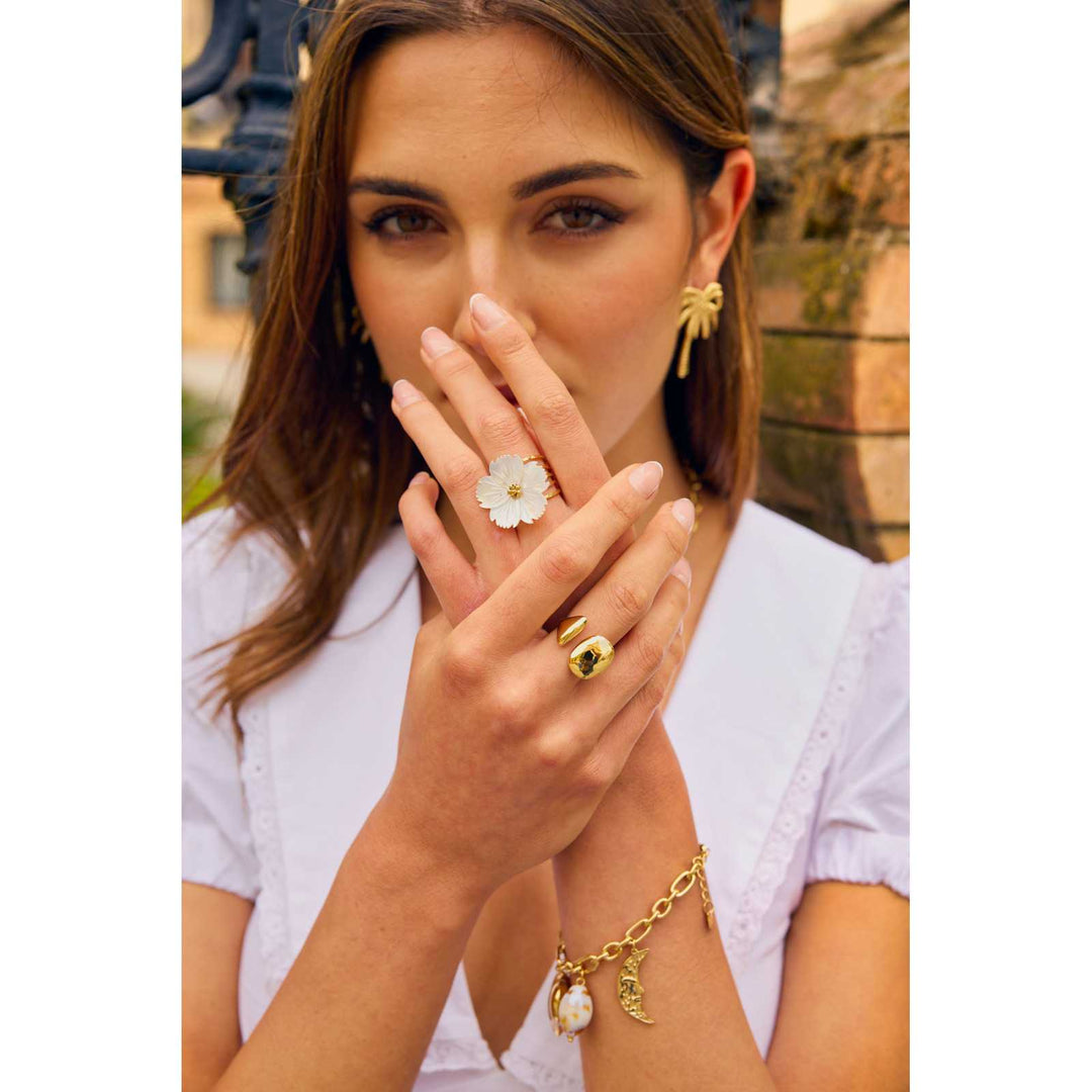Femme portant une bague marguerite en nacre blanche et doré sur la main – bague réglable en acier inoxydable résistante à l’eau