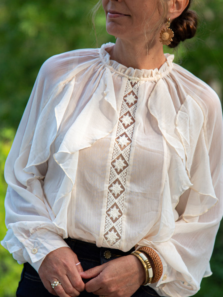 Détail de la blouse écru à volants avec empiècement brodé et manches longues fluides