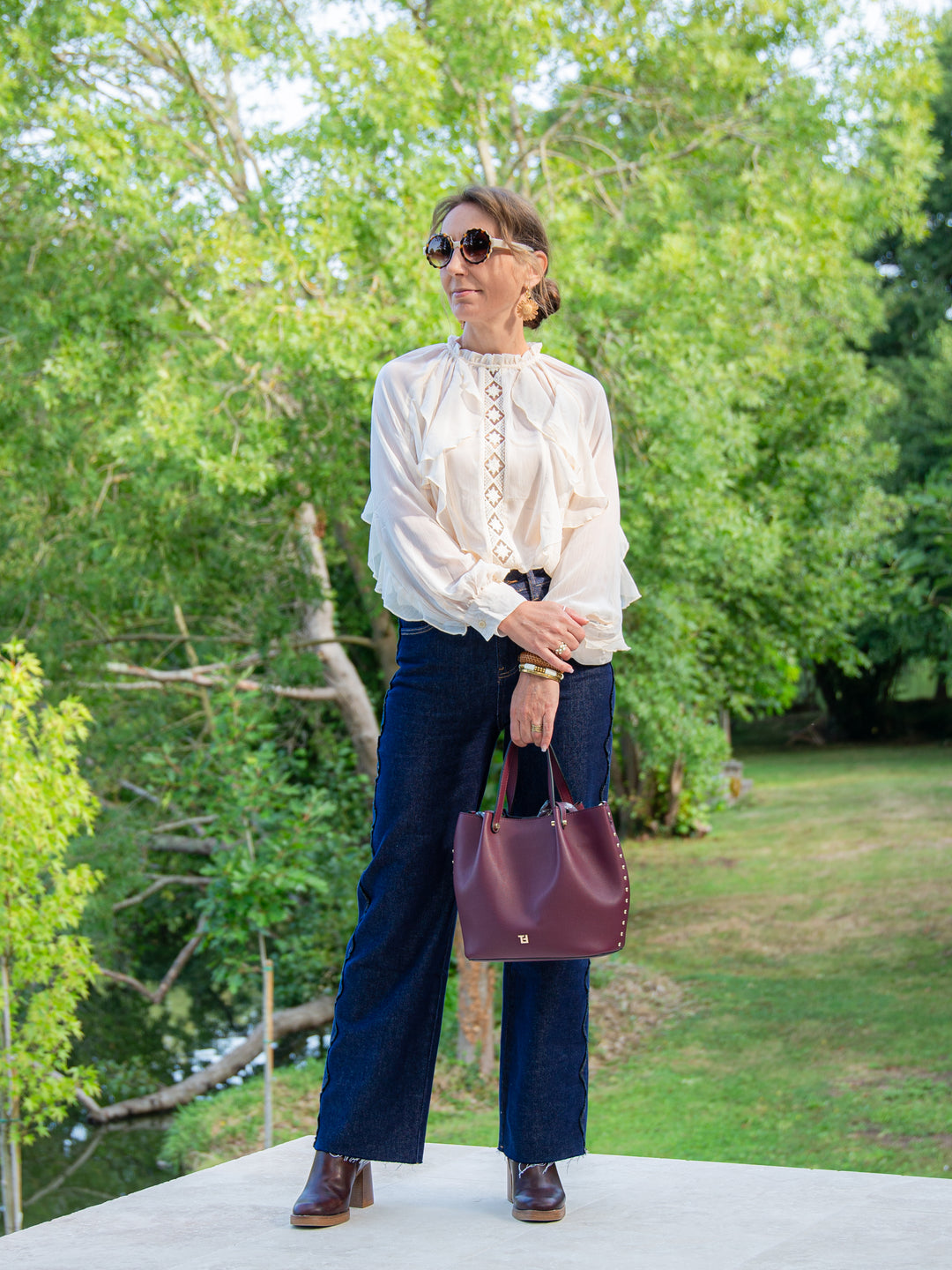 Femme élégante en blouse écru à volants avec jean brut et bottines à talons
