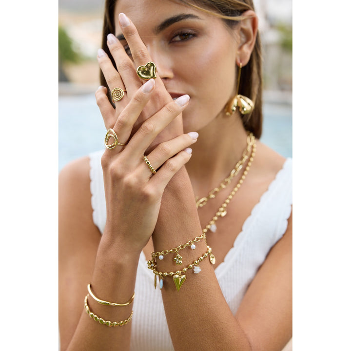 Femme portant un bracelet doré en acier inoxydable à maille perlée avec breloques cœur et œil – bijou tendance, hypoallergénique et résistant à l’eau