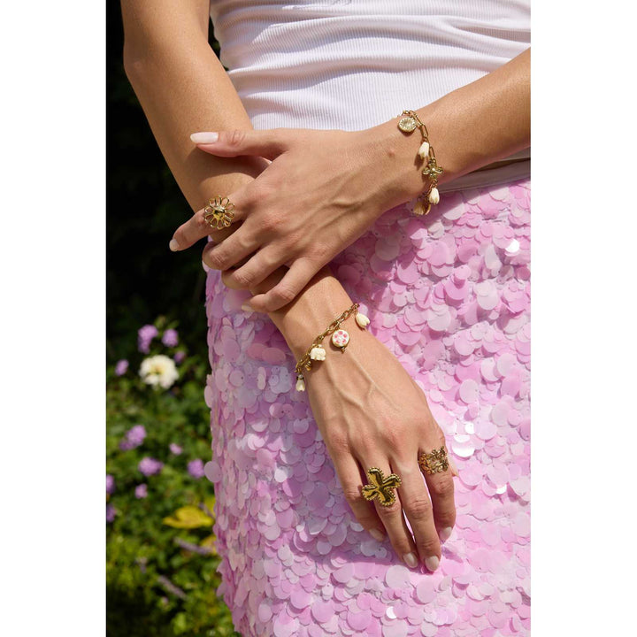 Femme portant un bracelet doré et blanc en acier inoxydable avec breloques soleil, cœur et fleurs – Bijou élégant et tendance