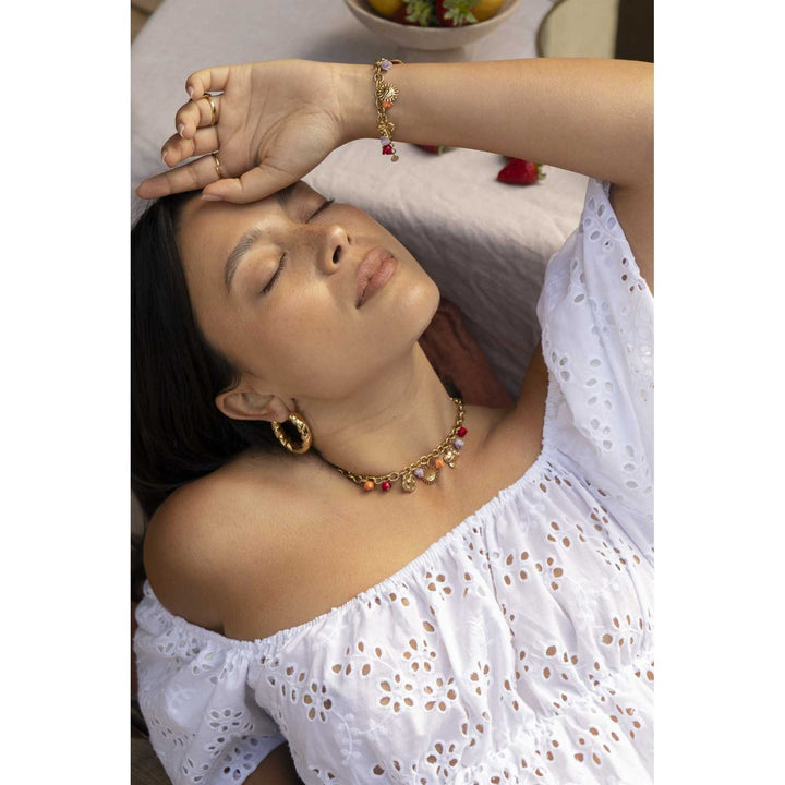 Femme portant un bracelet doré à breloques jonquille multicolores rouge, rose et orange en acier inoxydable, résistant à l’eau