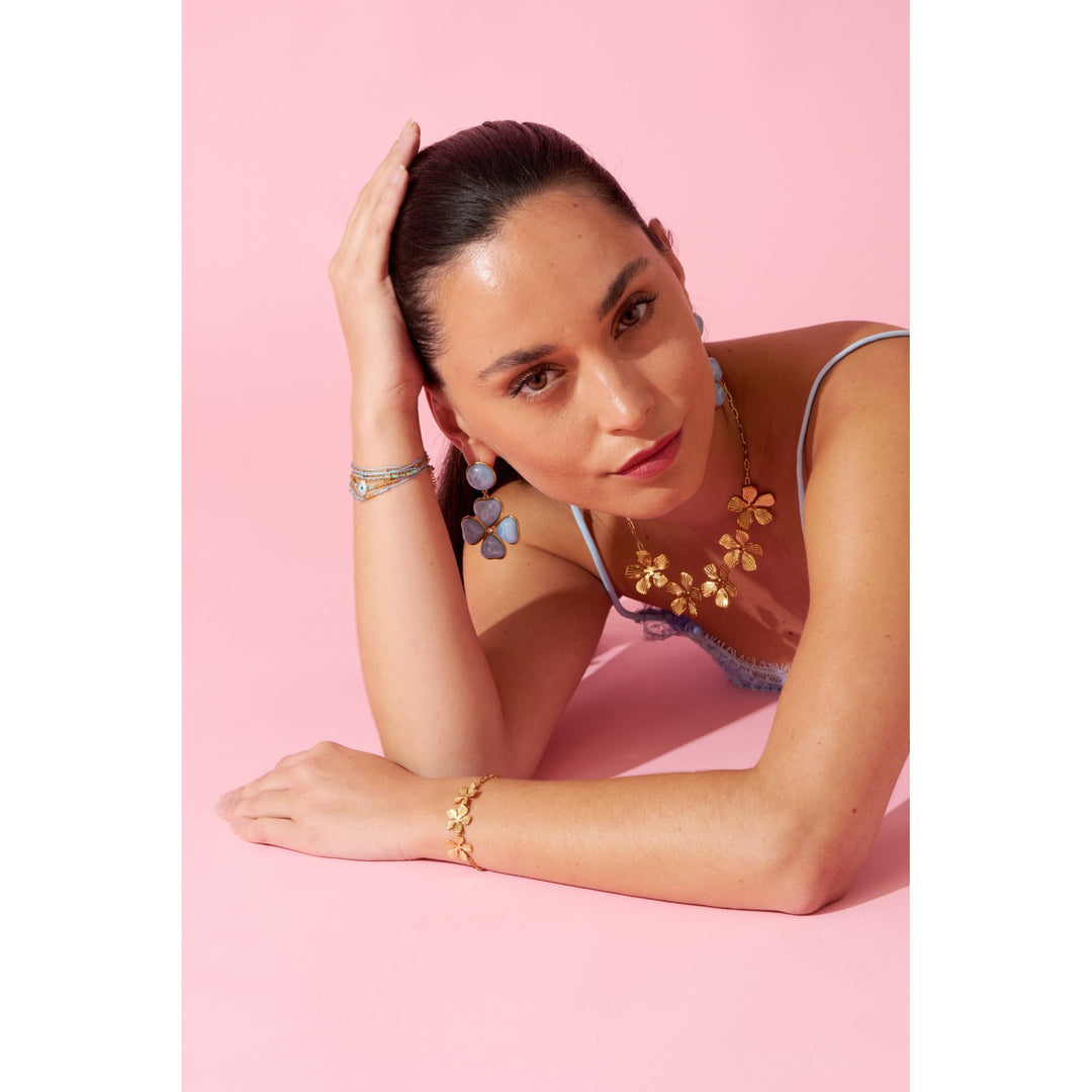 Femme portant un bracelet doré en acier inoxydable avec trois fleurs élégantes, bijou hypoallergénique résistant à l’eau