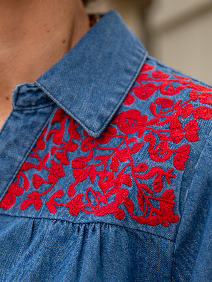 gros plan sur le col d’une chemise en jean femme avec broderie florale rouge
