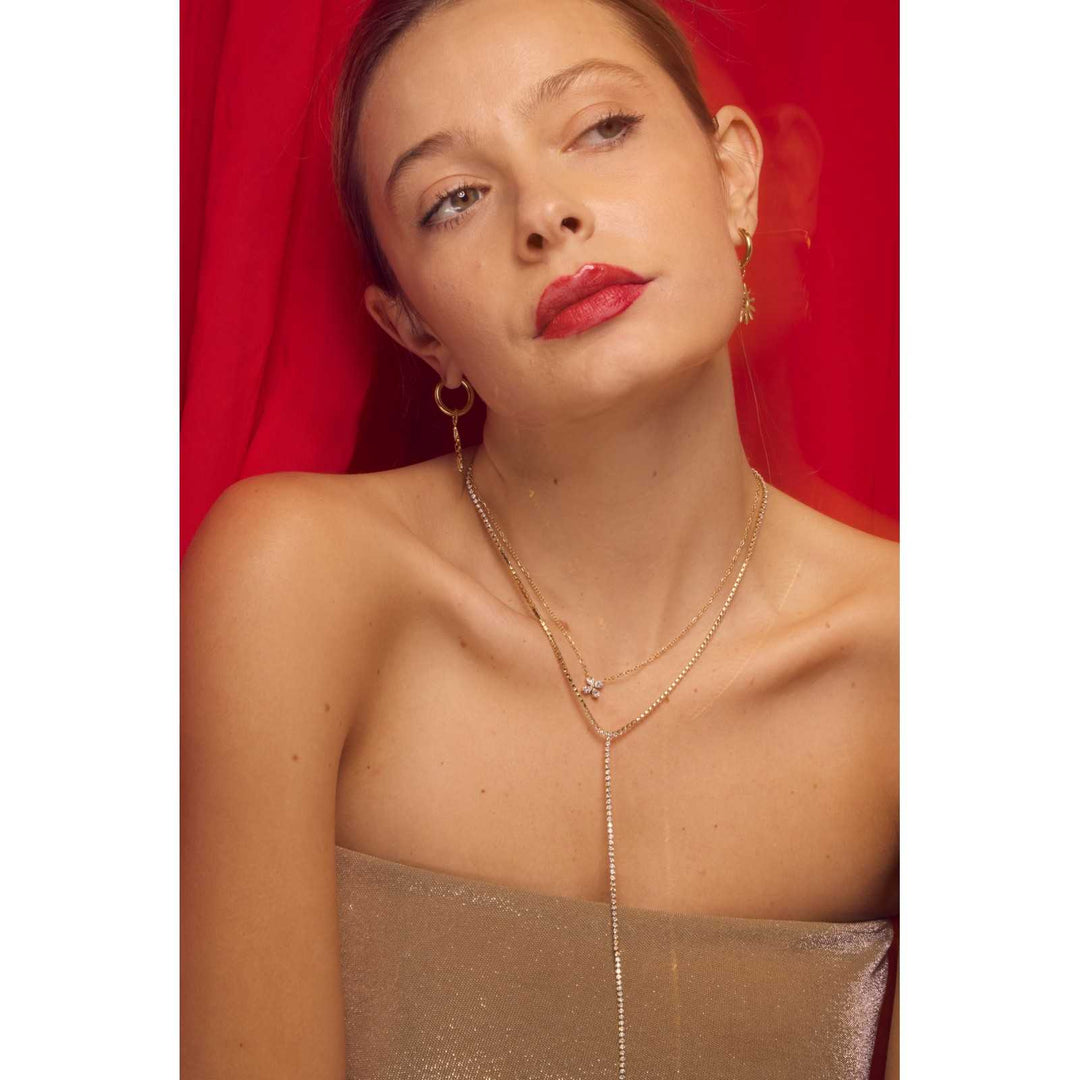 Femme portant un collier doré en acier inoxydable avec pendentif trèfle à strass blancs – Bijou discret et élégant