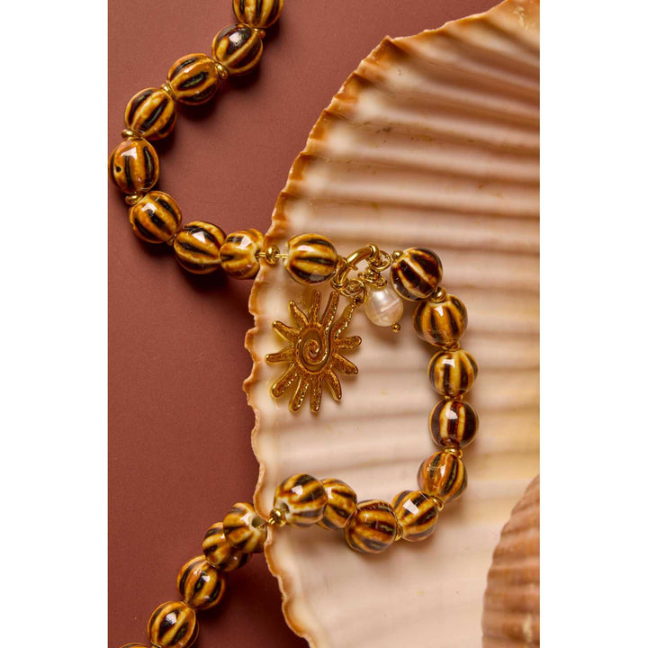 Brown and black zebra bead necklace with gold sun charm and white pearl