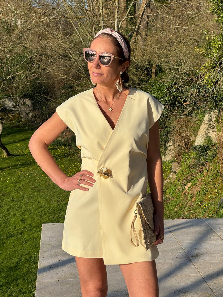 Combishort jaune portefeuille col V avec bouton bijou à la taille qui cintre la silhouette, tenue élégante idéale pour le printemps et l’été