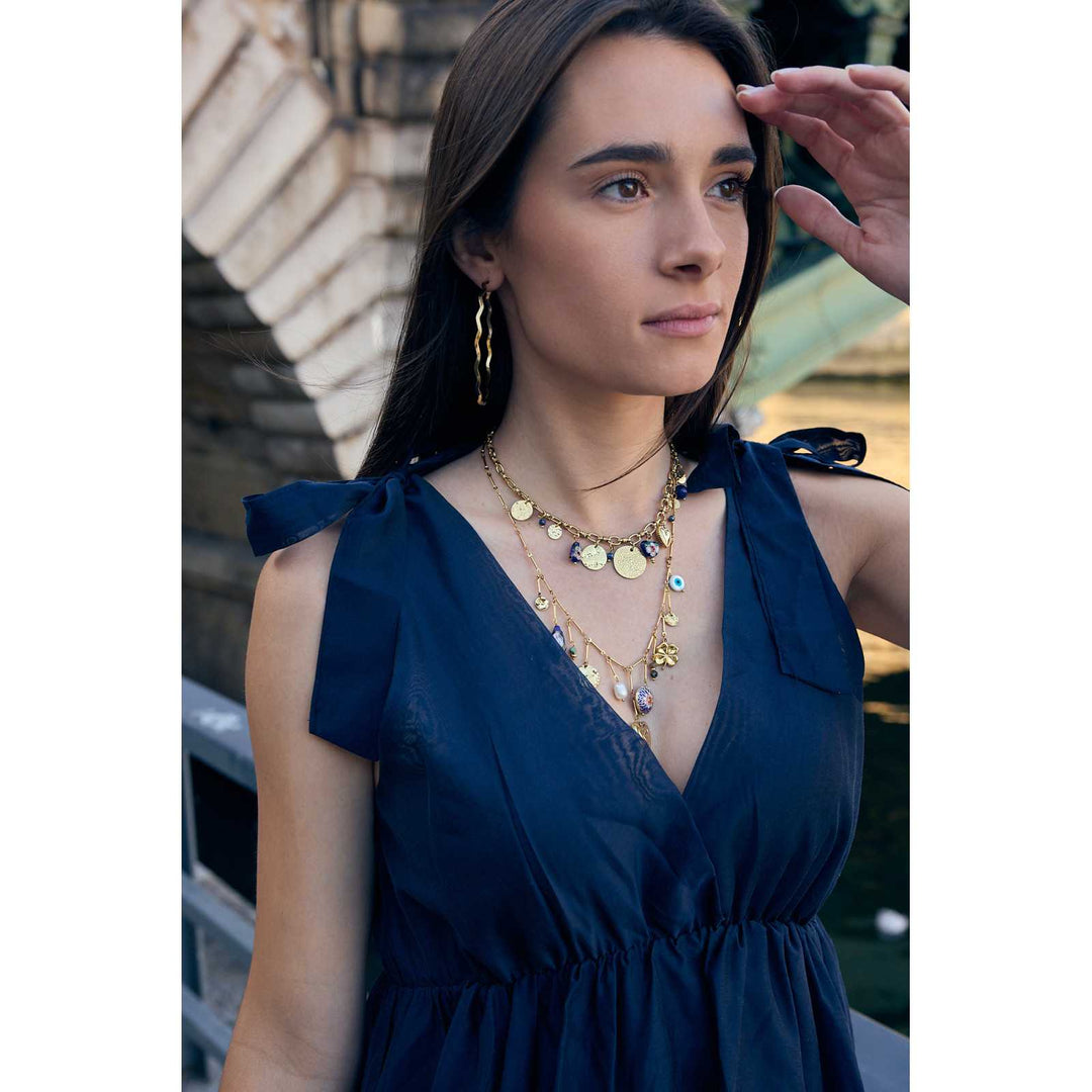 Femme en robe bleu marine portant un collier doré à breloques élégantes – Look mode été chic
