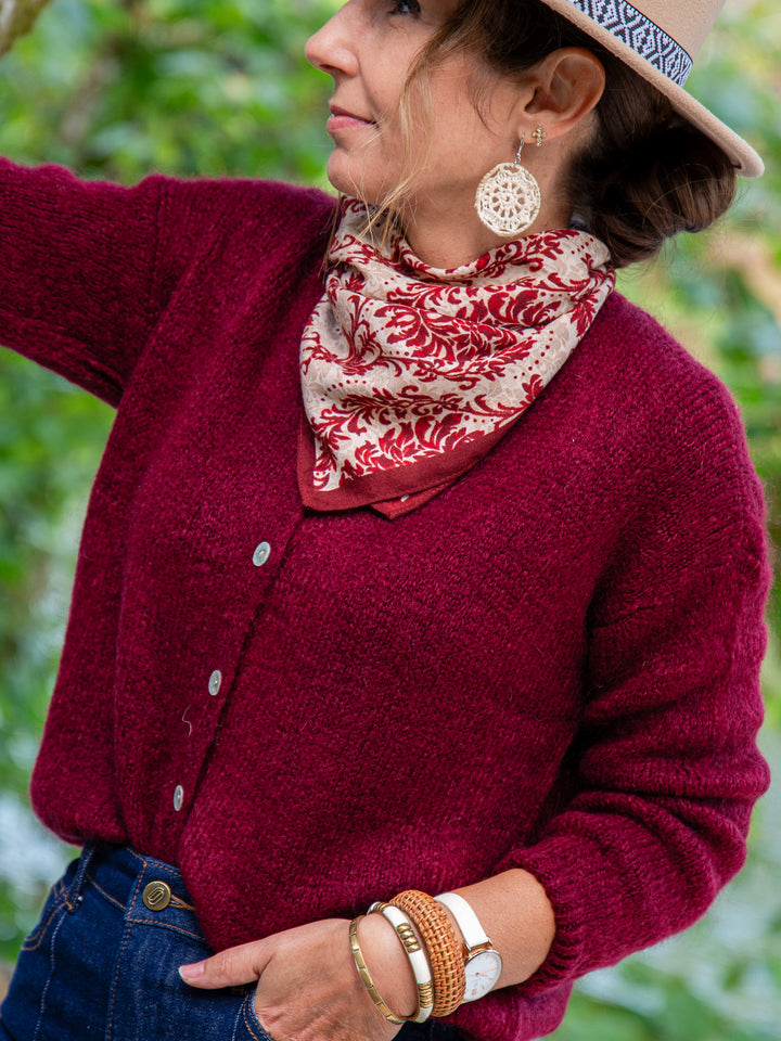 Gros plan gilet bordeaux femme avec foulard imprimé et bijoux bohème chic