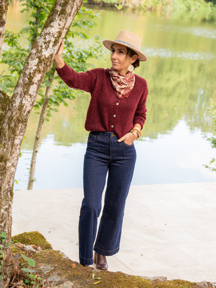 Gilet bordeaux femme porté avec un jean taille haute et chapeau beige tendance automne