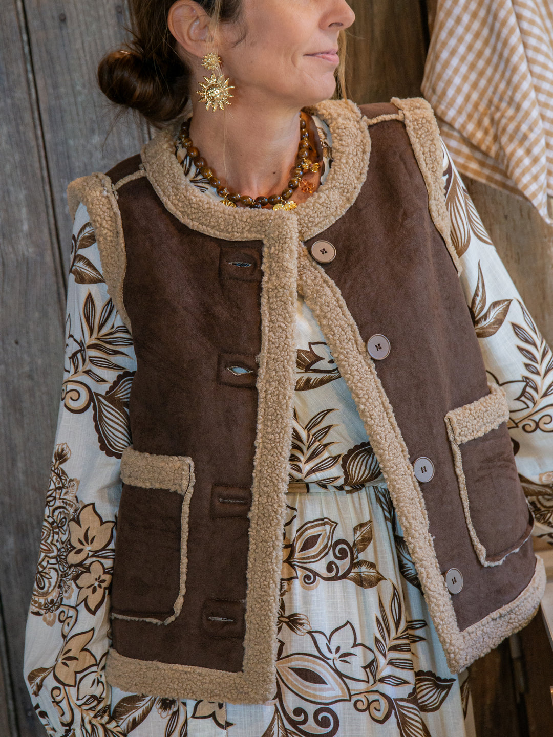 femme portant un gilet sans manches marron doublé effet mouton sur une robe fleurie bohème, look automne chic