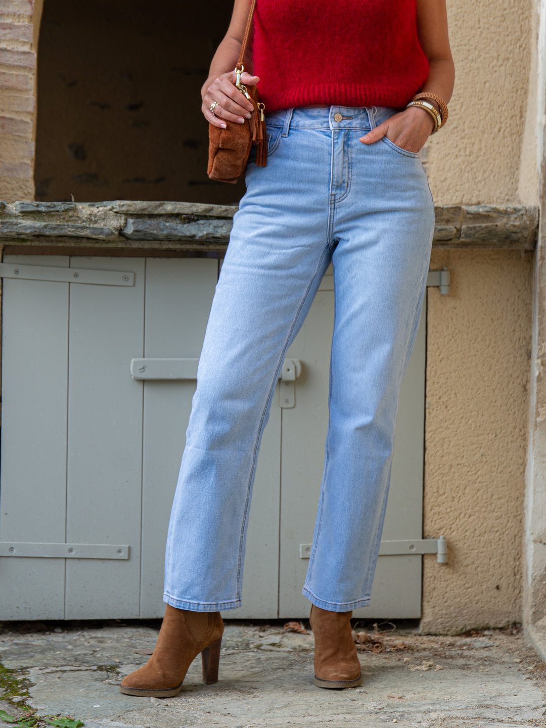 Jean Solange Oraije en denim clair, coupe droite taille haute, associé à un pull rouge sans manches.