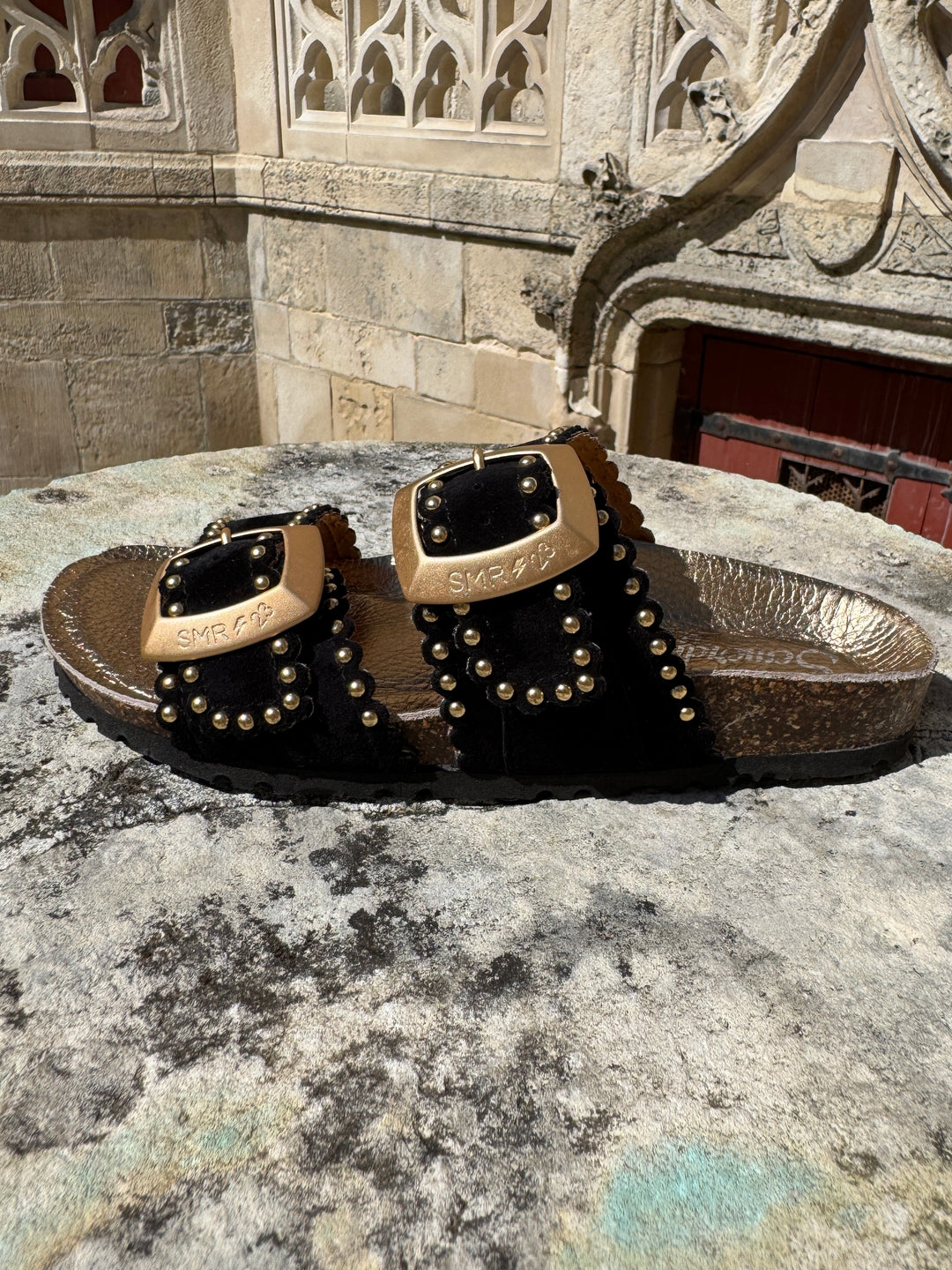 Mules en cuir noir à clous dorés avec brides réglables ARONA Semerdjian, logo SMR23 sur les boucles