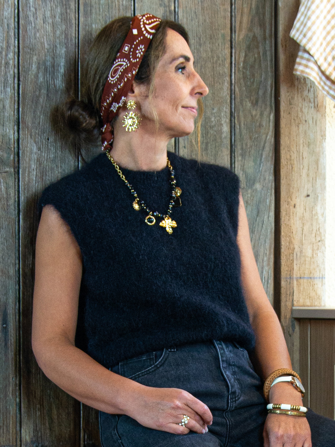 Pull sans manches noir femme vue de profil avec accessoires dorés De La Mode