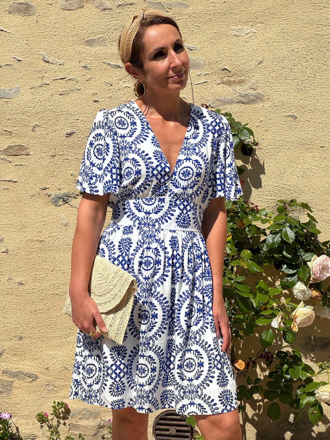 Robe courte blanche à imprimé floral bleu, col V et coupe empire. Fluide et légère, cette robe allie élégance et confort idéal pour l'été
