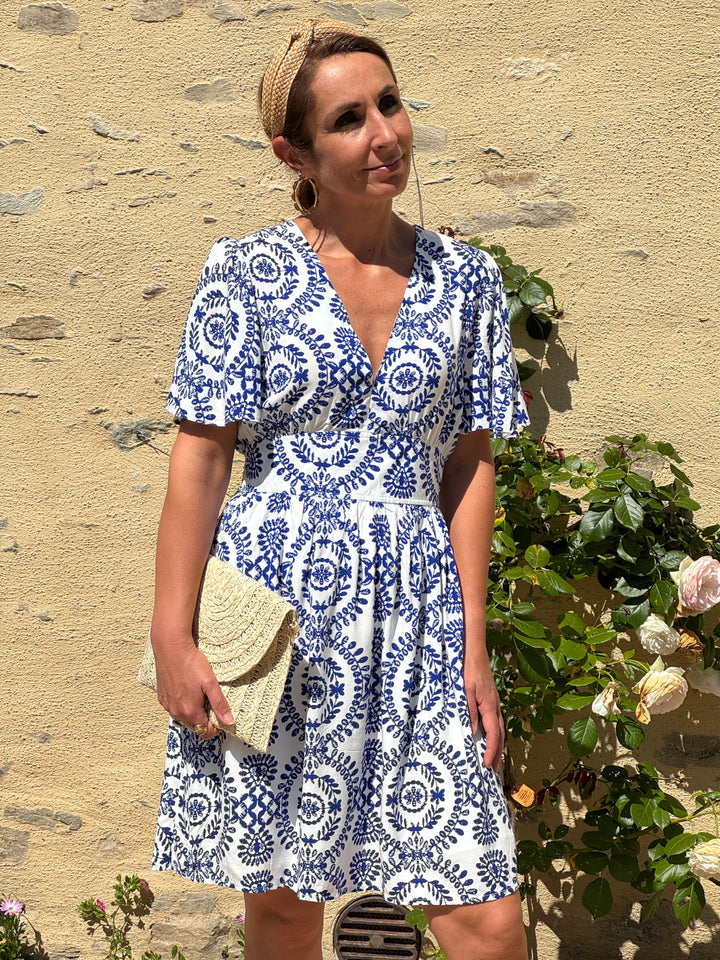 Robe courte blanche à imprimé floral bleu, col V et coupe empire. Fluide et légère, cette robe allie élégance et confort idéal pour l'été