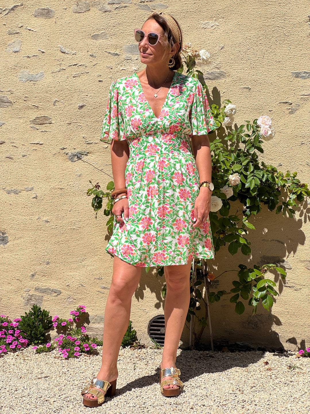 Robe courte In April 1986 à imprimé floral vert, rose et orange sur fond blanc, coupe empire, col V et manches courtes.