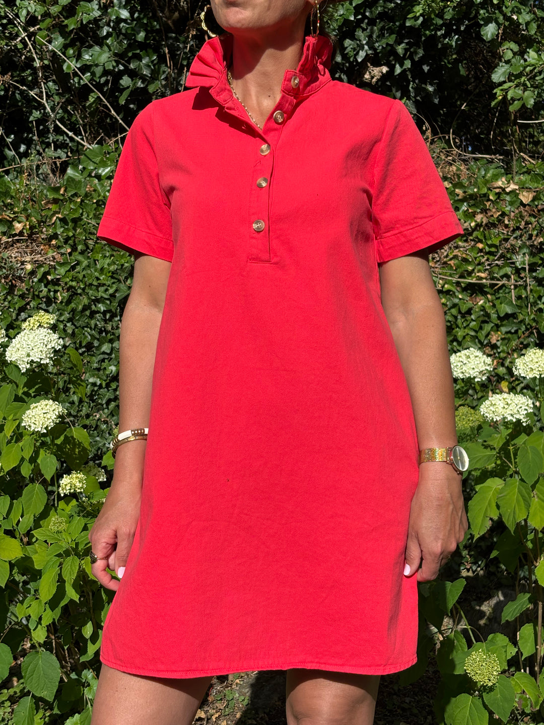 Robe courte rouge à la coupe trapèze avec col montant volanté, manches courtes et denim léger. Une pièce élégante et confortable, idéale pour l’été.