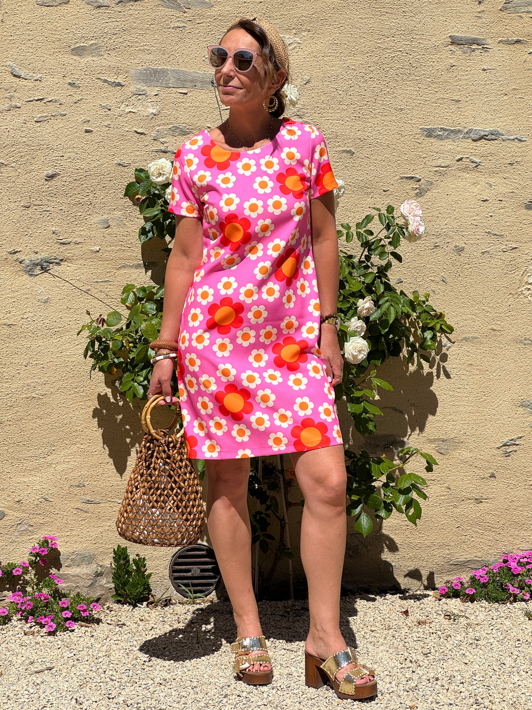 Robe courte Hippocampe à imprimé fleuri seventies écru et orange sur fond fuchsia, coupe droite, col rond et manches courtes.