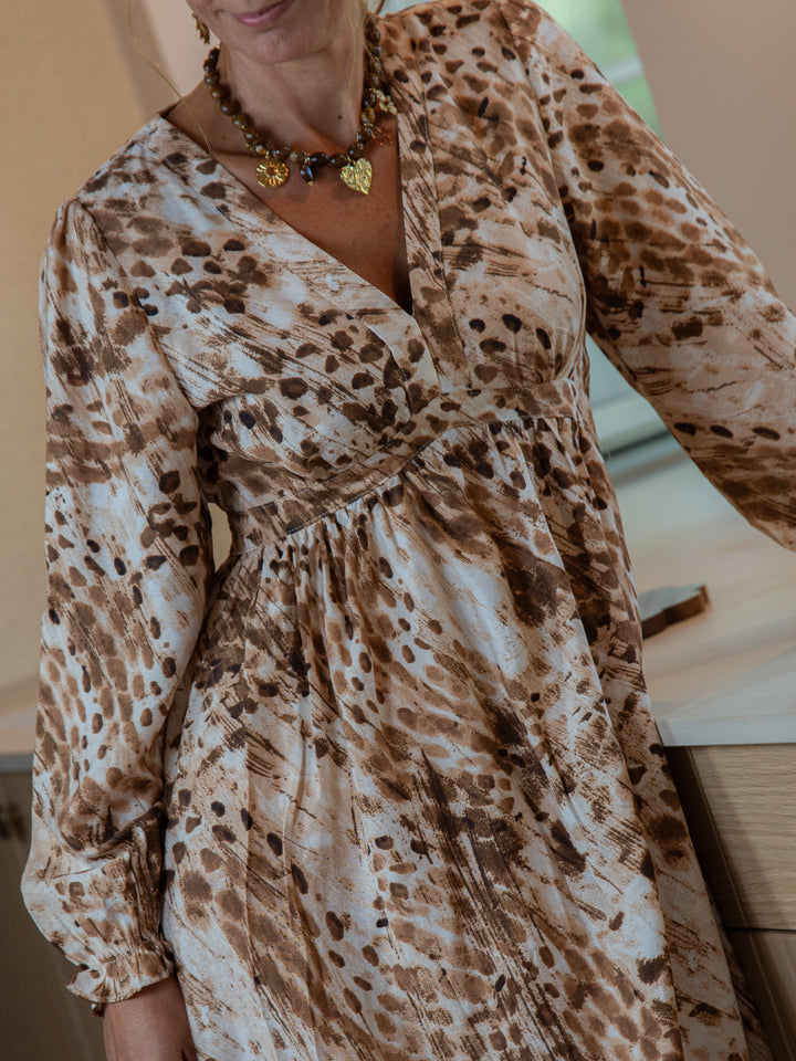 femme portant une robe longue bohème chic marron et blanc avec décolleté cache-cœur et manches longues