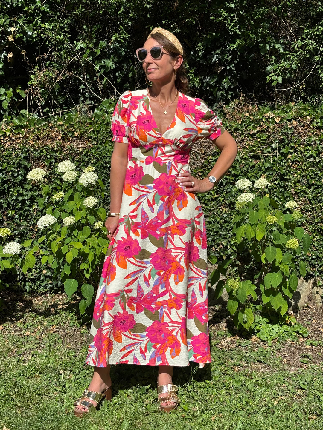 Robe longue fluide à imprimé floral multicolore sur fond beige, avec col V, coupe empire, manches courtes et fente sur le côté. Une robe légère et élégante idéale pour l’été.