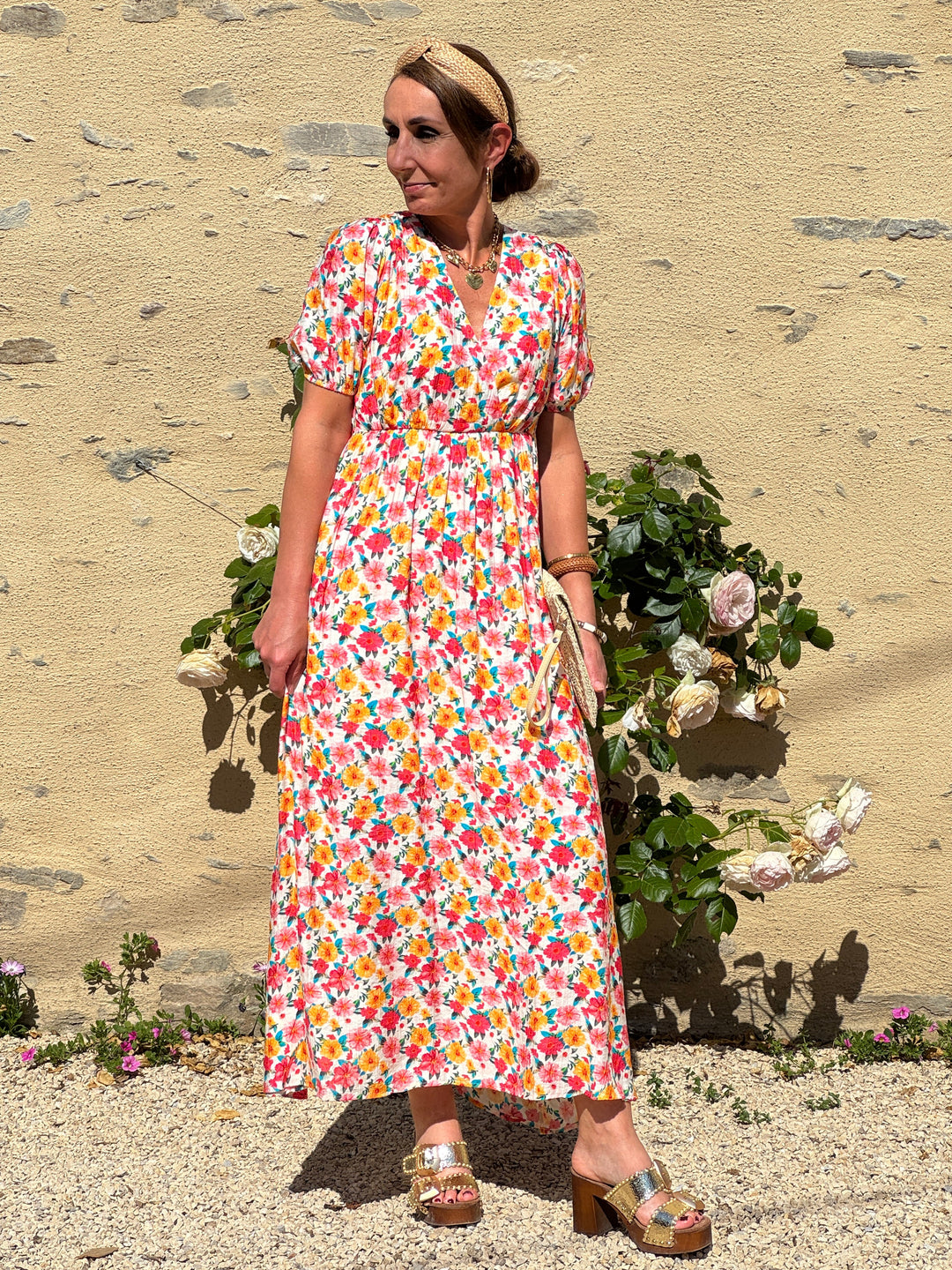 Robe longue à imprimé floral multicolore pastel sur fond beige, avec col V devant et dos, coupe empire et manches courtes. Une robe fluide et légère, idéale pour l’été.