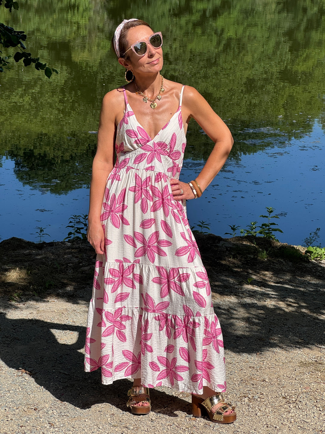 Robe longue beige à imprimé floral rose avec fil lurex doré, col V, fines bretelles réglables et coupe empire. Une robe fluide et légère, parfaite pour l'été.