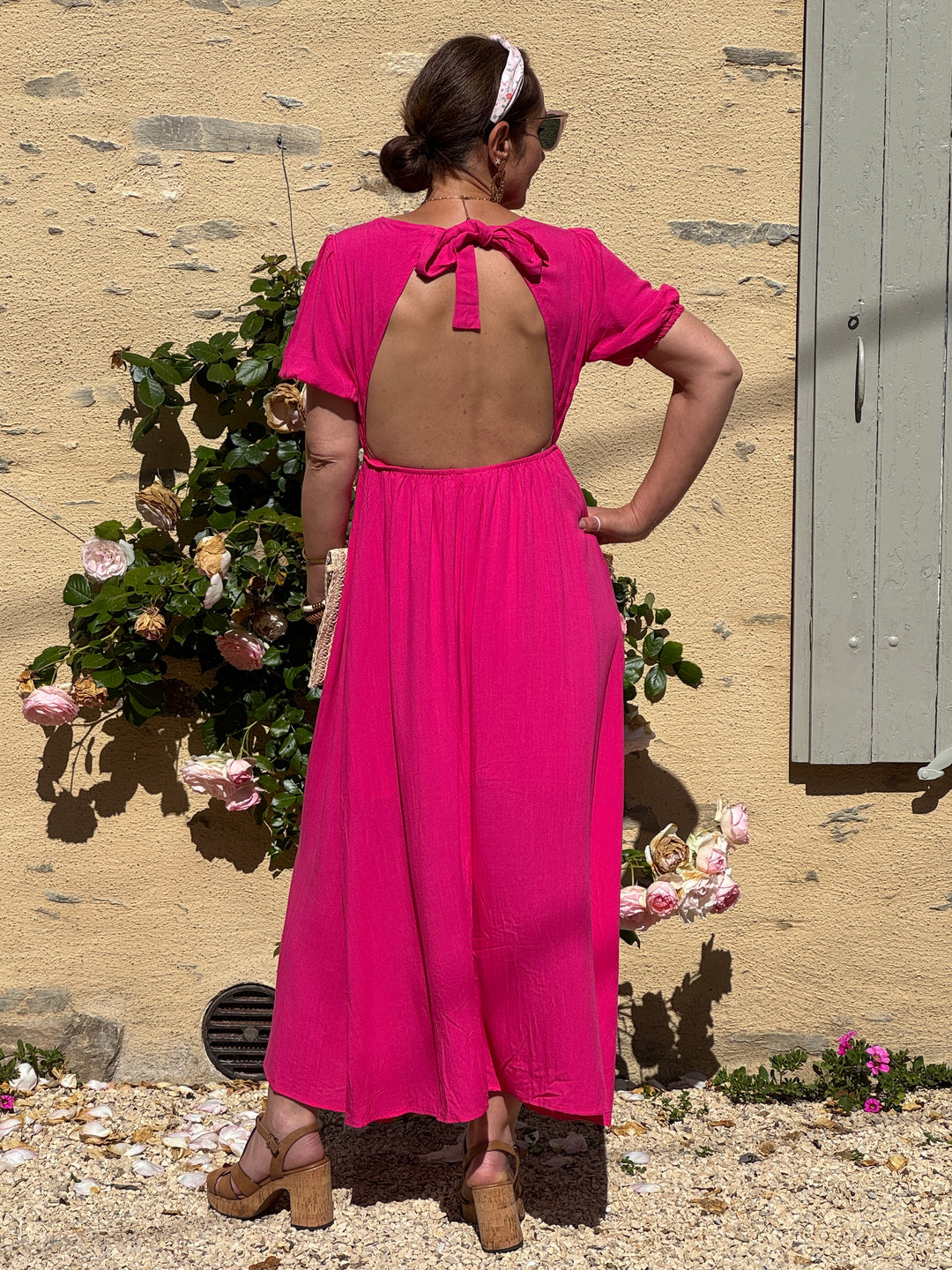 Robe longue fuchsia fluide et légère avec col V, manches courtes élastiquées, dos ouvert avec nœud et coupe ample élégante, idéale pour un look d’été.