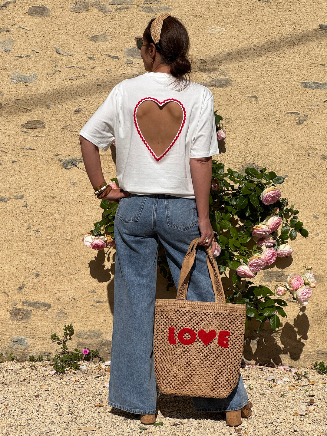 Tee-shirt blanc à manches courtes avec col rond et grand cœur ajouré brodé rouge dans le dos, coupe droite confortable et tendance pour l’été.
