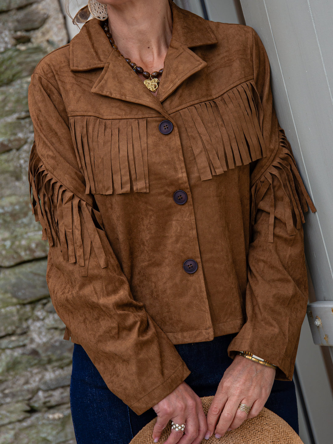 gros plan sur une veste à franges en suédine marron pour femme, tendance bohème chic