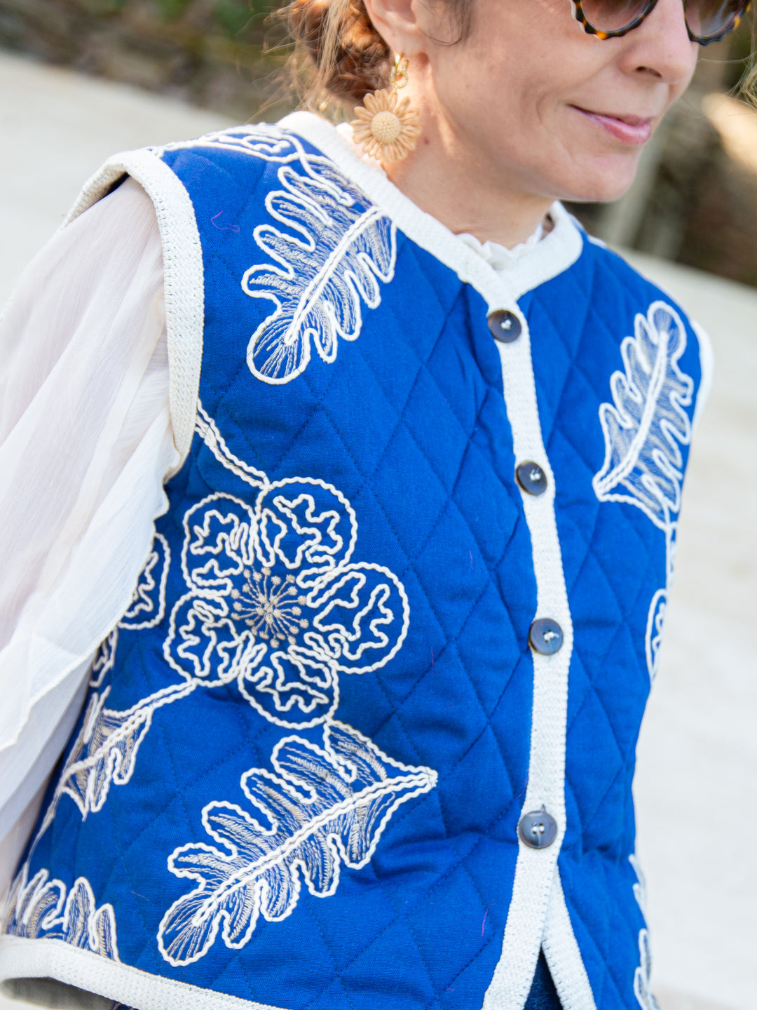 Vue rapprochée de la veste sans manche matelassée bleu avec broderies florales blanches