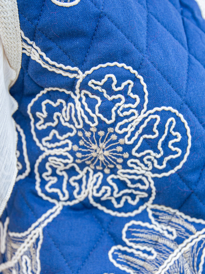 Zoom sur la broderie fleurie blanche de la veste sans manche matelassée bleu femme chic